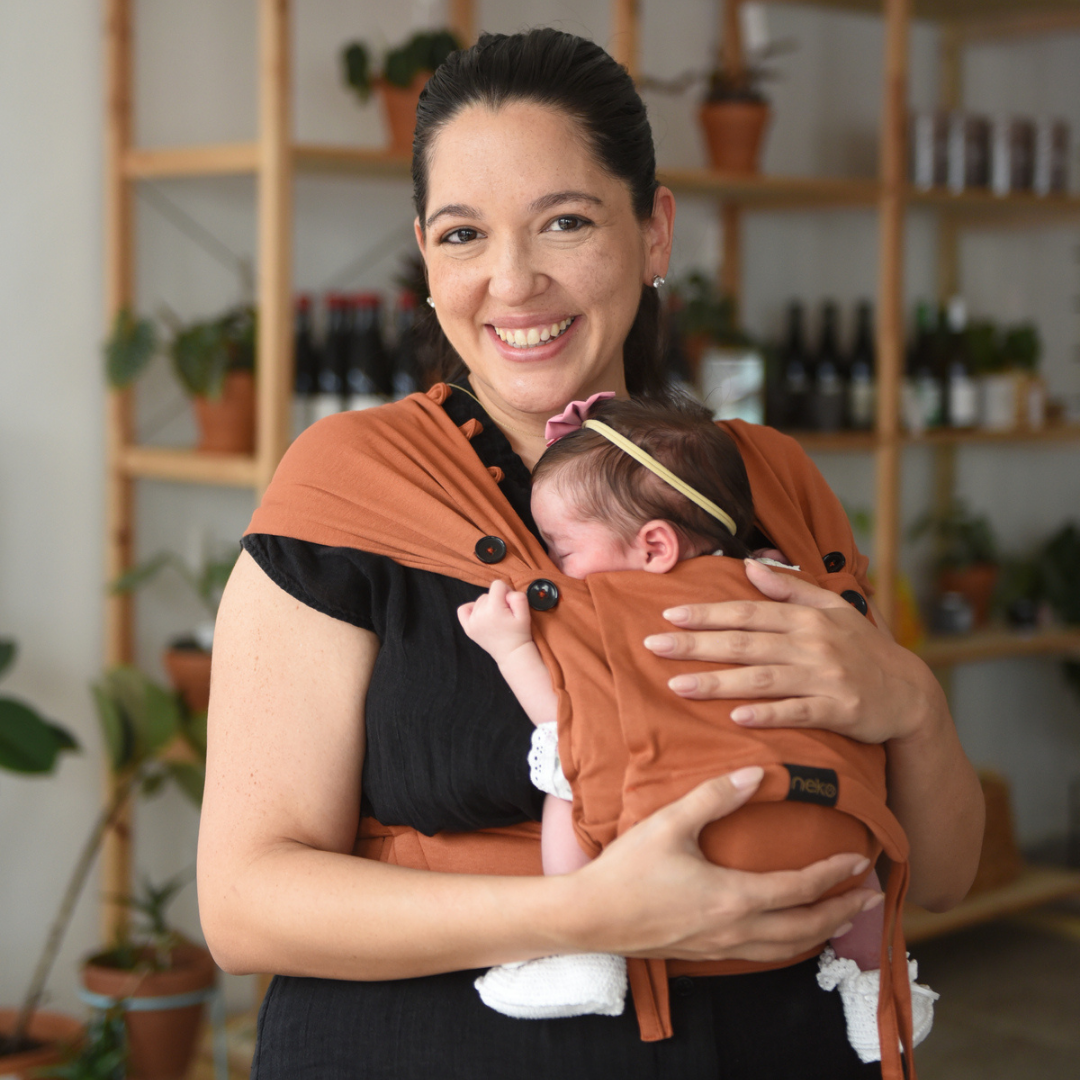 Eltern tragen ihr Neugeborenes in der Neko Tiny Babytrage in Cinnamon – sanft, ergonomisch und anschmiegsam.