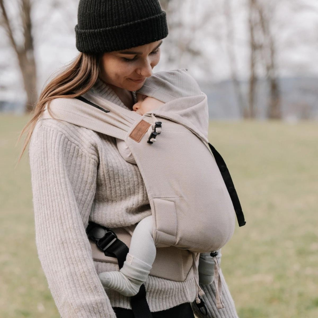 Mutter trägt ihr Baby in der Hoppediz Primeo Full-Buckle-Trage – sicher, bequem und mit natürlicher Anhock-Spreiz-Haltung.