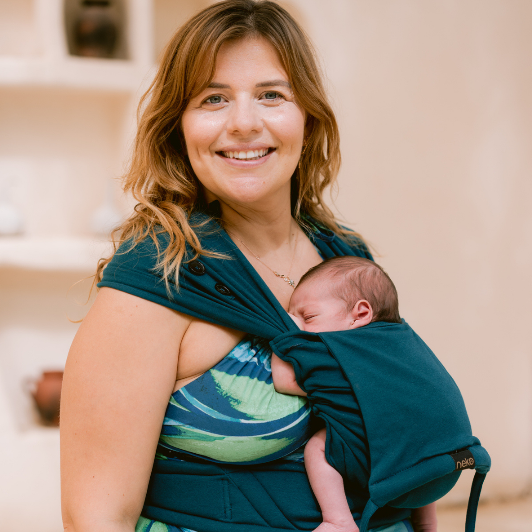 Eltern tragen ihr Neugeborenes in der Neko Tiny Babytrage in Evergreen – sanft, ergonomisch und anschmiegsam.